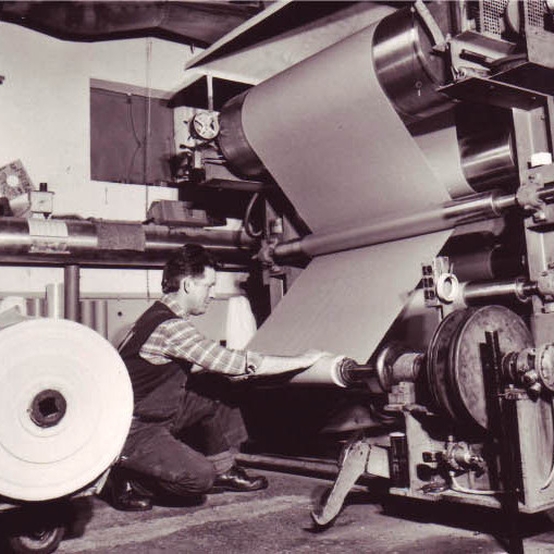 Mitarbeiter an einer historischen Papierverarbeitungsmaschine